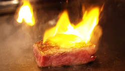 自慢の黒樺牛ステーキを炎で包んで香りづけするフランベ